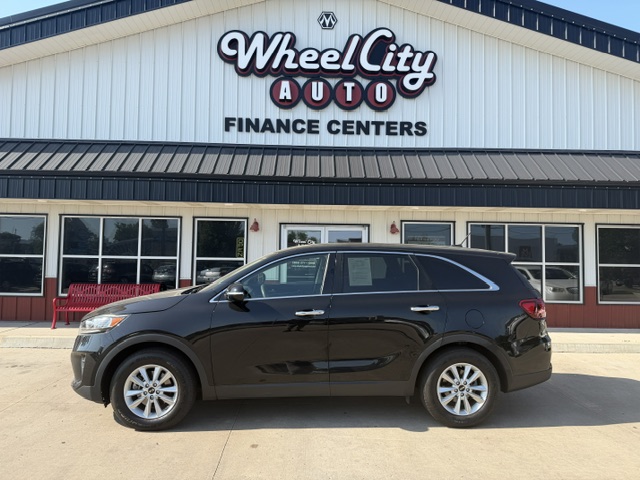 Black SUV parked in front of the Wheel City Auto Finance Centers dealership storefront.