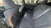 Rear interior of a car with gray fabric seats and three-seat bench, front seats visible and seat belts fastened.