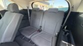 Interior of a car showing the gray fabric rear bench with two headrests, seat belts and a window to the outside behind the seats.