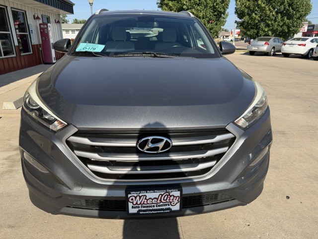 Front view of a gray Hyundai SUV parked in a dealership lot; Wheel City license plate frame visible.