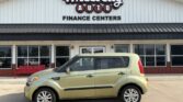 Beige compact car parked in front of Wheel City Auto Finance Centers storefront with large signage above.