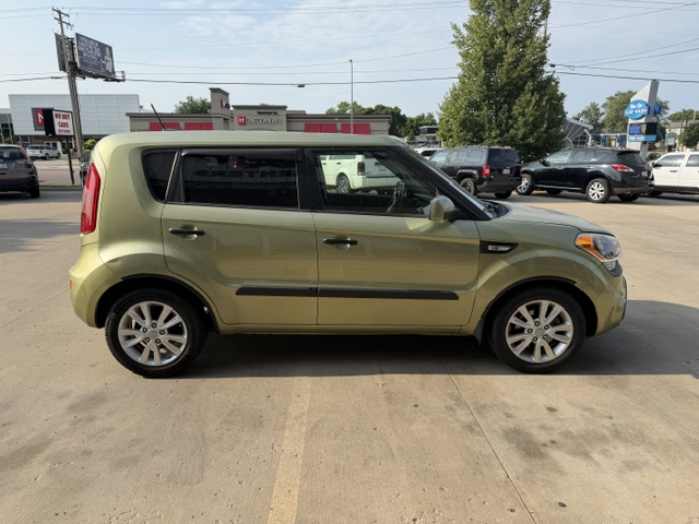 Side view of a gold compact SUV parked in a dealership lot with other cars nearby.