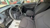 Interior of a Kia car from the driver's side: steering wheel, dashboard, center console, two front seats, door panel, and a floor mat with footprints visible