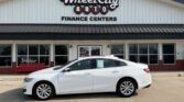 White sedan parked in front of Wheel City Auto Finance Centers storefront.