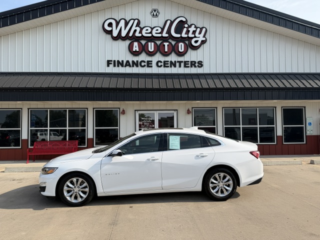 White sedan parked in front of Wheel City Auto Finance Centers storefront.