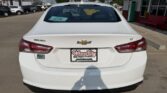 Rear view of a white Chevrolet Malibu LT at a car dealership, with Wheel City license plate frame and a price tag visible in the rear window.