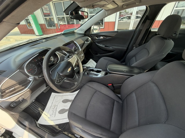 Interior of a Chevrolet with black fabric seats, steering wheel, dashboard, and center console visible from the driver's side.