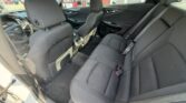 Interior of a mid-size car showing the back seat with gray fabric upholstery and seat belts visible, front seats in view.