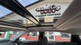 From inside a car, looking up through the sunroof at a building that reads ‘Wheel City Auto Finance Centers’ in large lettering above the entrance.