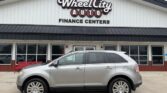Silver SUV parked in front of Wheel City Auto Finance Centers storefront with large sign above the entrance.