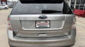 Rear view of a silver Ford Edge Limited SUV in a dealership lot; Wheel City Auto Finance Centers license plate frame, rear wiper, and dual exhausts visible.