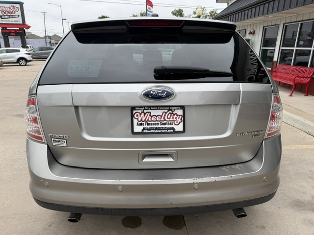 Rear view of a silver Ford Edge Limited SUV in a dealership lot; Wheel City Auto Finance Centers license plate frame, rear wiper, and dual exhausts visible.
