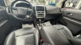 Interior of a car with black leather seats, steering wheel, and central console featuring a gear shifter and radio controls, viewed from the front passenger area.