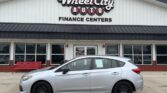 Silver sedan parked in front of Wheel City Auto Finance Centers storefront at a car dealership.