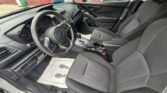 Front interior of a sedan showing the driver’s seat, steering wheel, and center console with the gear shifter and cup holders.