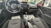 Front interior of a Subaru car with left-side steering wheel, center touchscreen, gear shifter, and dark fabric seats.