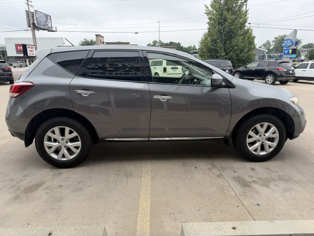 Side view of a gray mid-size SUV with tinted windows and alloy wheels parked in a dealership lot.