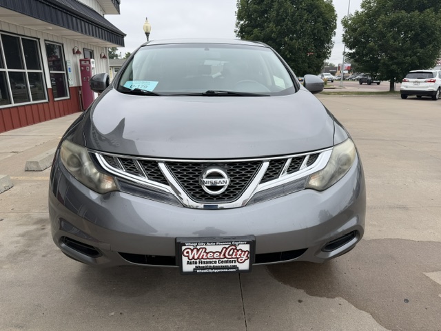 Gray Nissan SUV facing camera in a dealership lot, front view with Wheel City license plate frame.