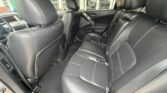Rear row of black leather seats in a car with a center armrest and headrests, viewed from the back left door.