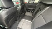 Black leather rear interior of a car with three seats, visible seat belts, and front seats in view; dealership outside the window.