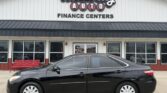 Black four-door sedan parked in front of Wheel City Auto Finance Centers storefront, signage visible above the building front.