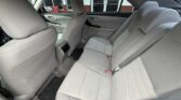 Rear interior of a gray sedan with three cloth seats, headrests, and visible seat belts; front seats and door panels also shown.