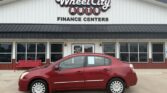 Red four-door sedan parked in front of the Wheel City Auto Finance Centers storefront.