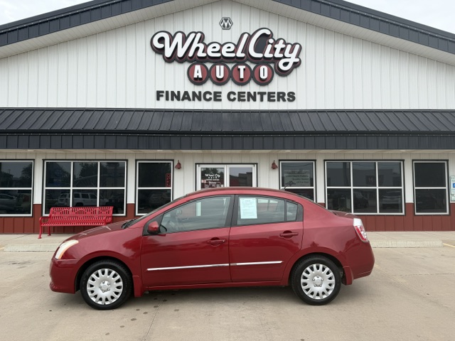 Red four-door sedan parked in front of the Wheel City Auto Finance Centers storefront.