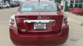 Rear view of a red Nissan Sentra in a dealership lot, with a Wheel City license plate frame and a price sticker on the rear window.
