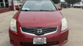 Front view of a red Nissan sedan in a dealership lot with a Wheel City Auto Finance Centers plate frame visible on the front bumper.