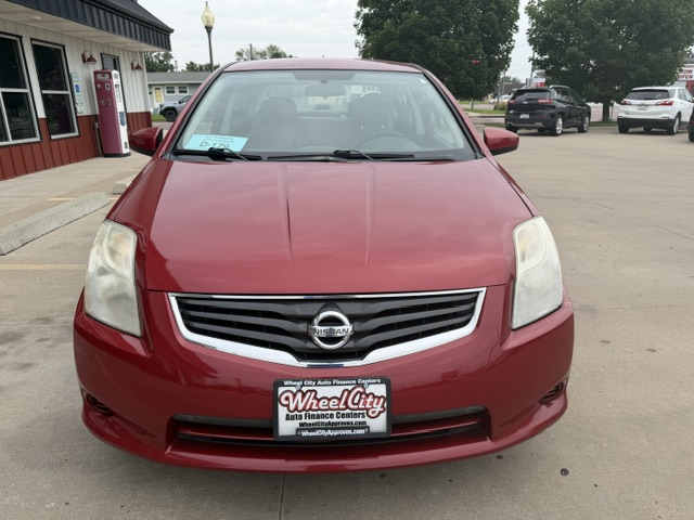 Front view of a red Nissan sedan in a dealership lot with a Wheel City Auto Finance Centers plate frame visible on the front bumper.