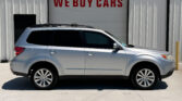 Silver SUV parked in front of a building with a large 'WE BUY CARS' sign above the doorway, empty lot.