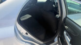 Open car door reveals the gray interior of a sedan with front seats and steering wheel visible