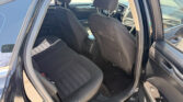 Interior of a black car seen from the open rear door, showing the front seats with headrests and dashboard in the background.