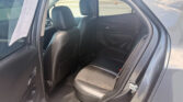 Open rear door reveals black leather back seat of a SUV with outside parking lot visible through windows.