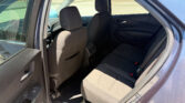 Open rear passenger door showing the car’s back seats and headrests in dark fabric, with a view of the outside pavement and building beyond the window.