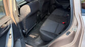 Rear passenger seating area of a car with black cloth seats and an open rear door; appears clean and empty apart from floor mats Add optional dash area into view.