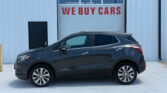 Gray SUV parked in front of a light-blue building with a large 'WE BUY CARS' sign on the garage door, front-facing view