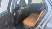 Rear seating area of a car with black and tan leather seats, open door, daytime parking lot outside visible through windows.