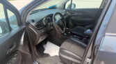 Open-car interior: driver’s side view with steering wheel, dashboard, and center console visible; outside parking lot scene through windows.