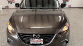Front view of a brown Mazda SUV in a showroom with Wheel City Auto Finance Centers backdrop signage behind it.