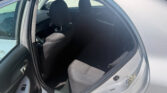 Open rear passenger door showing the back seat with dark gray fabric, two headrests, and a sunlit interior panel of a sedan.