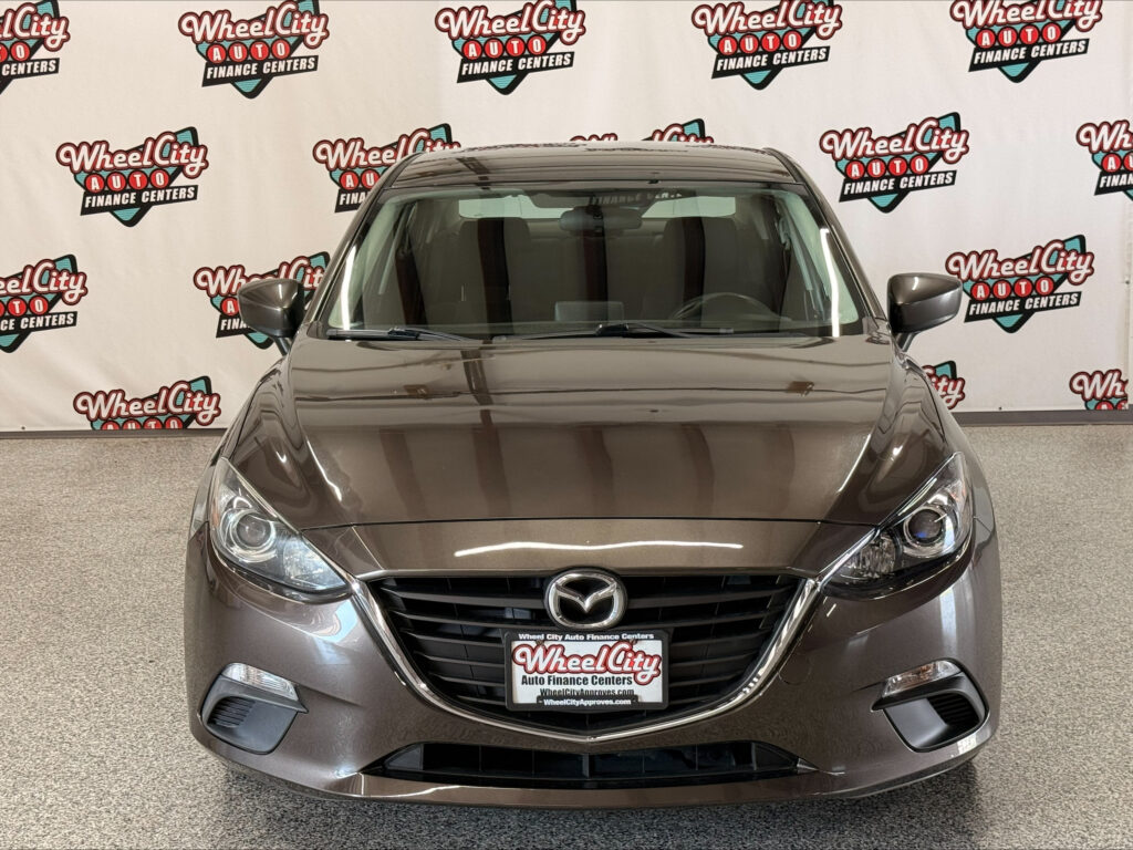 Front view of a gray Mazda SUV in a showroom with a Wheel City Auto Finance Centers backdrop.