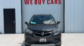 Gray Buick SUV parked in front of a white garage door with a large red 'WE BUY CARS' sign above it