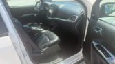 Interior view of a white SUV showing front seats, center console, and steering wheel from the open driver’s side door.