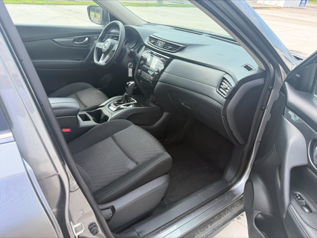 Interior of a dark SUV showing driver’s seat, steering wheel, center console, and dashboard.