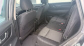 Interior view of a car's rear seating area with black cloth seats and headrests, seen from the open rear door
