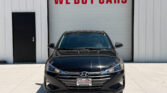 Front view of a black Hyundai sedan parked in front of a white building with a large 'WE BUY CARS' sign above the bay door