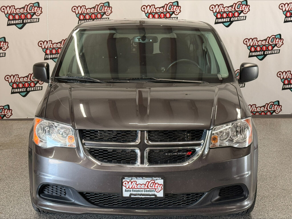 Front view of a gray Dodge SUV indoors, with a Wheel City Auto Finance Centers backdrop visible behind the windshield