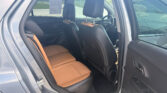 Interior of a dark gray SUV showing the back seat with brown leather upholstery and headrests, door open to the outside.